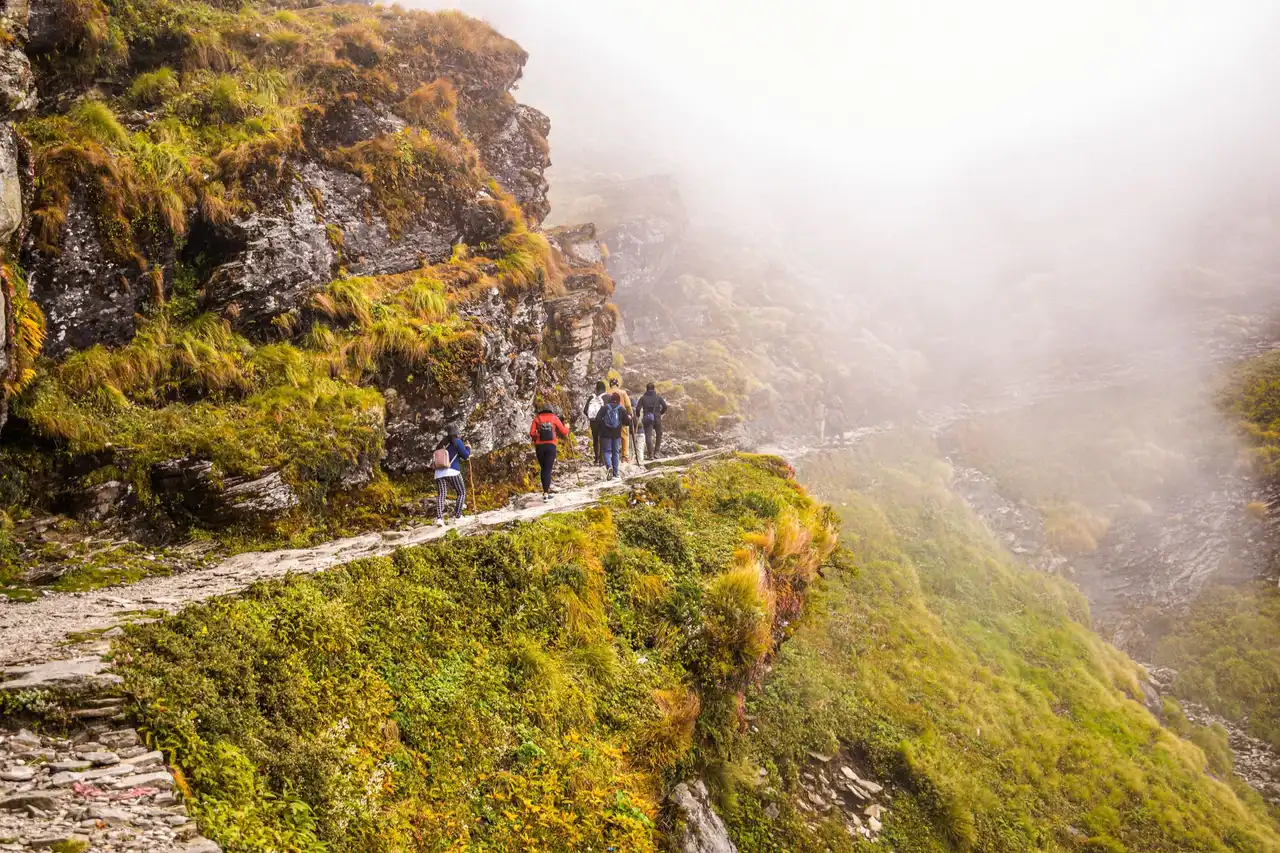 Trekkers walking a misty stone trail on the way to Tungnath