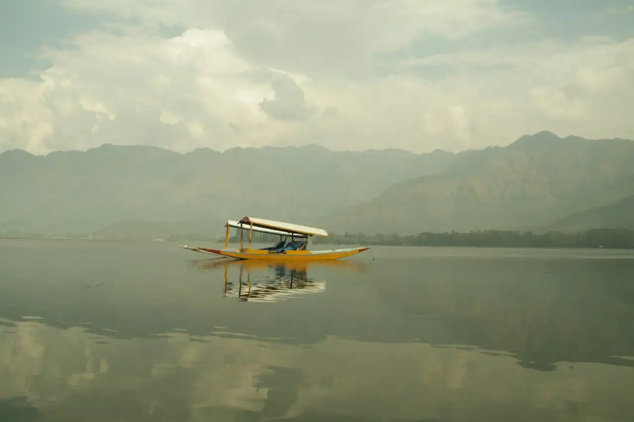 An empty shikara resting on the glassy water of Dal Lake
