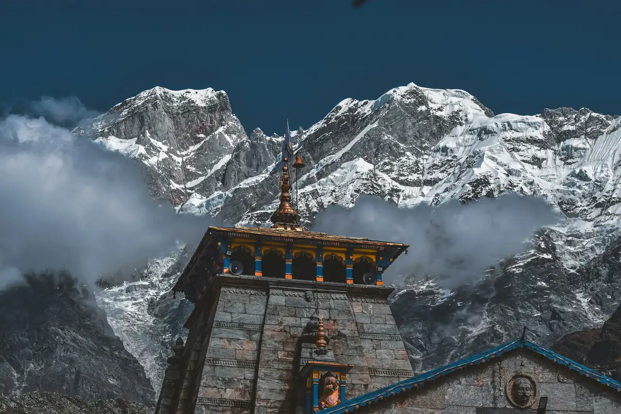 The stone spire of Kedarnath temple against cloud-wrapped snow peaks